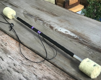 May include: A pair of black fire staffs with white, cotton-wrapped ends and purple tape accents. The staffs are connected by a black cord.