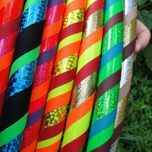 May include: A close-up of eight colorful hoops with different patterns and textures. The hoops are made of plastic and have a variety of colors, including red, green, blue, yellow, and black. The hoops are arranged in a row, with the top hoop being the largest and the bottom hoop being the smallest.