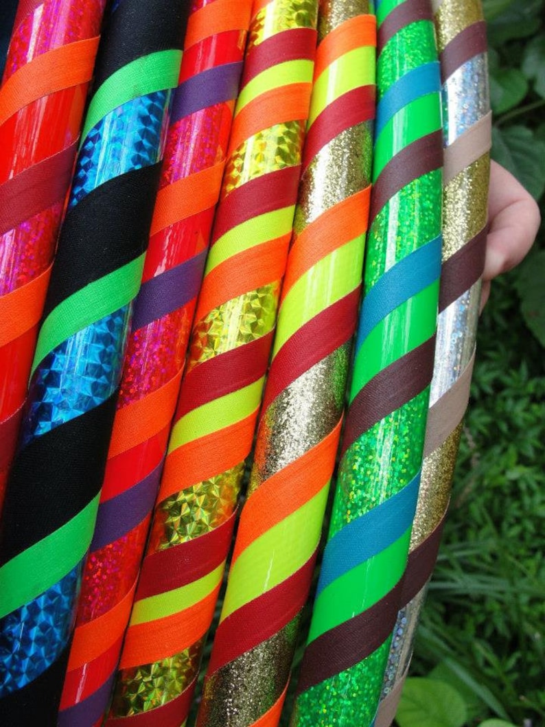 May include: A close-up of eight colorful hoops with different patterns and textures. The hoops are made of plastic and have a variety of colors, including red, green, blue, yellow, and black. The hoops are arranged in a row, with the top hoop being the largest and the bottom hoop being the smallest.