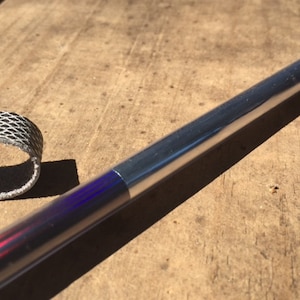 Può includere: Un bastone da passeggio argentato e arcobaleno con un cinturino nero.