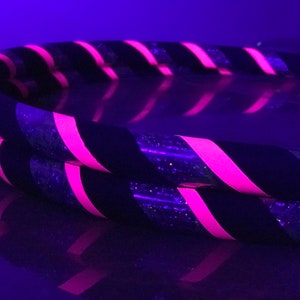 May include: Two black and pink striped hula hoops with glitter. The hoops are stacked on top of each other.
