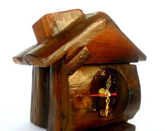 Könnte beinhalten: Eine Holzuhr in Form eines Hauses mit brauner Holzoptik. Das Zifferblatt der Uhr hat goldene Zeiger und schwarze Zahlen.