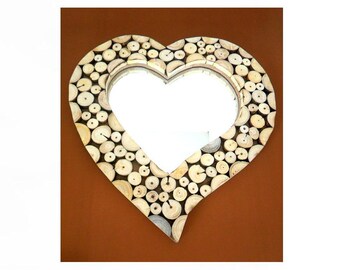 May include: A heart-shaped mirror with a wooden frame made of small, round pieces of wood. The mirror is surrounded by a brown background.