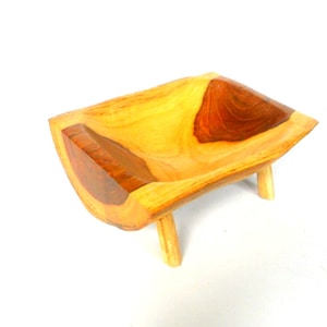 Puede incluir: Un cuenco de madera con un acabado de madera natural y un acento de madera marr&oacute;n oscuro. El cuenco est&aacute; sobre tres patas cortas.