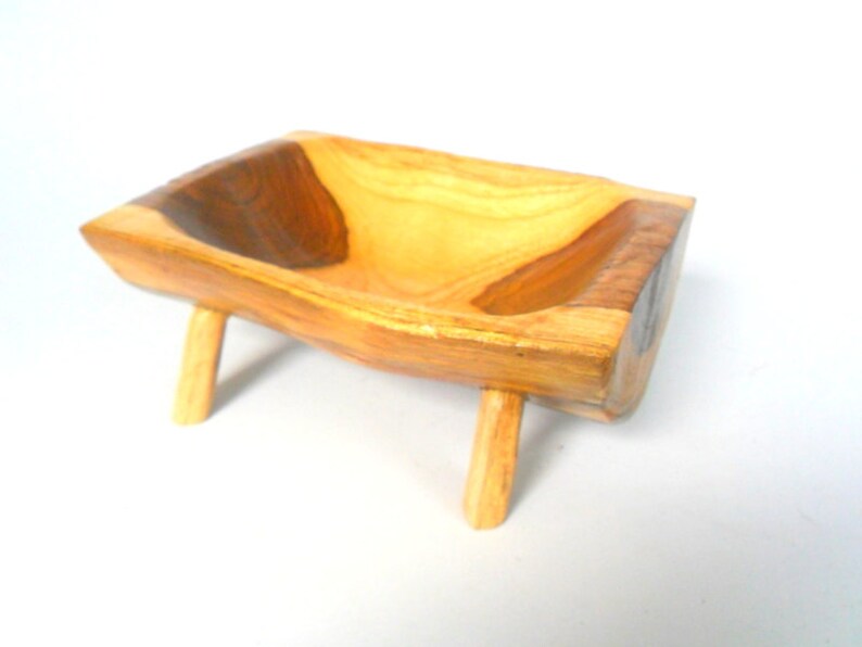 Puede incluir: Un cuenco de madera con un acabado de madera natural y un centro marr&oacute;n oscuro. El cuenco est&aacute; sobre cuatro patas cortas.