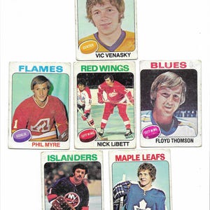 May include: A collection of vintage hockey trading cards featuring player portraits and team logos. The cards display names like Vic Venasky, Phil Myre, Nick Libett, Floyd Thomson, Glenn Resch, and Darryl Sittler. The cards have a retro design.