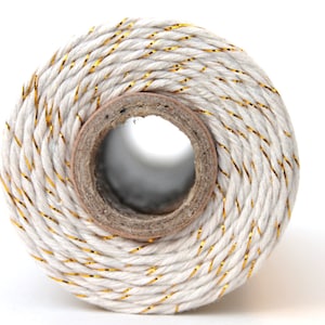 May include: A spool of white twine with gold metallic thread running through it.