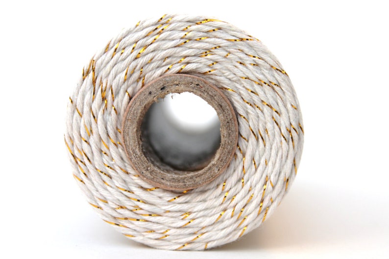 May include: A spool of white twine with gold metallic thread running through it.
