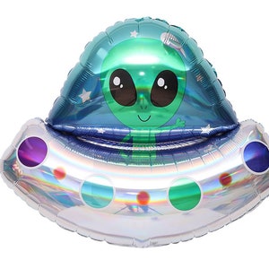 May include: A silver and blue iridescent foil balloon shaped like a UFO with a green alien inside. The alien has big eyes and a smile. The UFO has three round windows on the bottom.