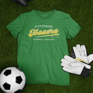 Może przedstawiać: Zielona koszulka z żółto-białym nadrukiem z napisem "Portwenn Tossers" oraz tekstem "Cornwall, England" i "Est. 2004" poniżej.