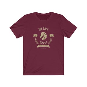 K&ouml;nnte beinhalten: Ein maroonfarbenes T-Shirt mit einer Vintage-Grafik eines Pferdekopfes mit dem Text "The Pale Horse", "15", "of", "Horse", "Much Deeping" und "England".