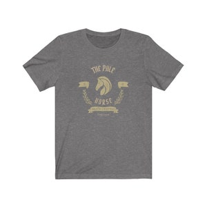K&ouml;nnte beinhalten: Ein heidefarbenes T-Shirt mit einer Vintage-Grafik eines Pferdekopfes mit dem Text "The Pale Horse" und "Much Deeping, England".