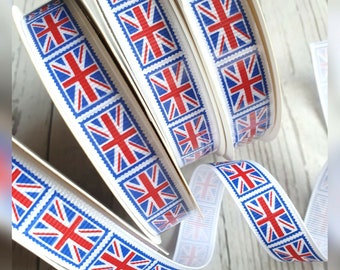 Puede incluir: Rollos de cinta blanca con un patrón repetido de banderas de la Union Jack rojas, blancas y azules en cuadrados azules.