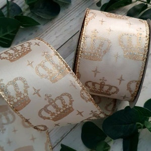 May include: Cream colored ribbon with a gold glitter crown pattern. The ribbon has a gold edge.