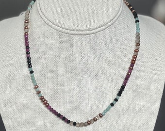May include: A multi-colored beaded necklace with black, brown, pink, and green beads.