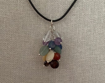 May include: A silver charm necklace with a cluster of colorful gemstone beads. The beads are arranged in a rainbow pattern, with clear, amethyst, blue, green, yellow, orange, and red beads.