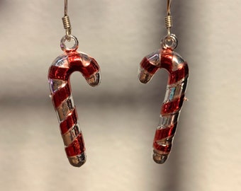 May include: A pair of silver dangle earrings shaped like candy canes with red and silver stripes.