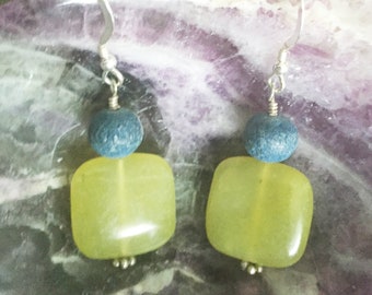 May include: A pair of dangle earrings with a light green square-shaped stone and a dark blue round stone on each earring.