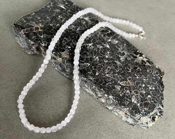 May include: A delicate necklace made of small, faceted, light pink rose quartz beads. The necklace is strung on a silver chain and is approximately 18 inches long.