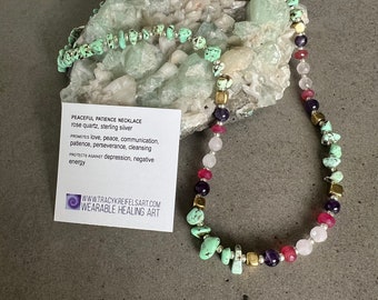 May include: A necklace made with green turquoise, pink rose quartz, purple amethyst, gold and silver beads. The necklace is on a white background with a card that reads "Peaceful Patience Necklace, rose quartz, sterling silver. Promotes love, peace, communication, patience, perseverance, cleansing. Protects against depression, negative energy. www.tracykreifelsart.com Wearable Healing Art."
