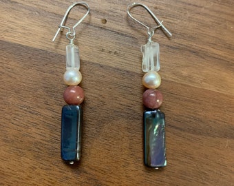 May include: A pair of silver dangle earrings with a clear crystal, a pink bead, and a dark iridescent rectangular bead.