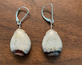 May include: A pair of silver dangle earrings with white and brown teardrop-shaped stones.