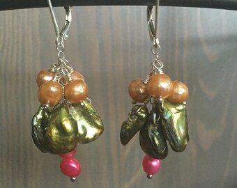 May include: A pair of dangle earrings with green, gold, and pink pearls. The earrings are made with silver wire and have a hook closure.
