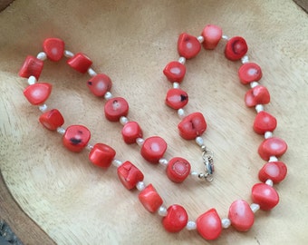 May include: A necklace made of red coral and white pearl beads. The necklace is strung on a silver chain with a lobster clasp.