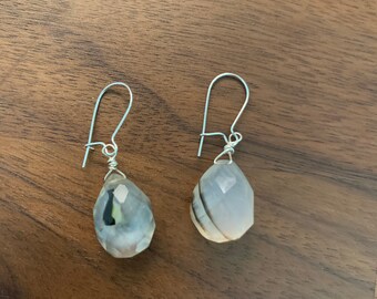 May include: A pair of silver dangle earrings with teardrop-shaped white agate stones with black and gray stripes.