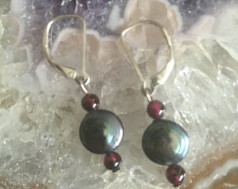 May include: A pair of silver dangle earrings with a dark grey pearl and two red garnet beads on each earring.