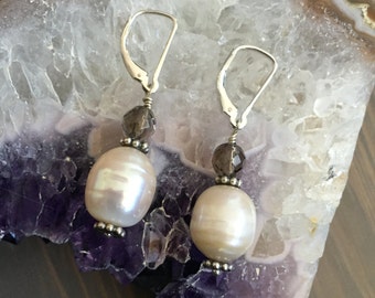 May include: A pair of silver dangle earrings with a white pearl and a smoky quartz crystal on each earring.