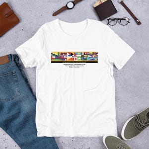 Puede incluir: Camiseta blanca con un diseño gráfico colorido con banderas y el texto "IN SOLIDARITY FOR A BETTER WORLD" y "ASIAN PACIFIC ISLANDER CLUB". La camiseta está hecha de un material suave, adecuada para el uso diario.