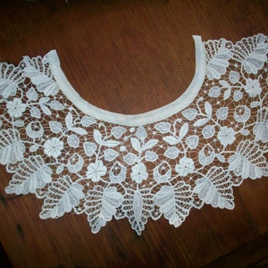 May include: White lace collar with a scalloped edge and floral design.