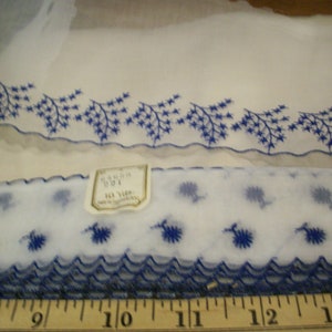 May include: A roll of white lace trim with a blue floral pattern. The trim is 10 yards long and is packaged with a white label that reads "Garden 591 10 Yds".