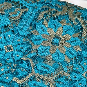 May include: Teal lace fabric with a silver floral pattern.