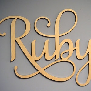 May include: A wooden sign with the name "Ruby" written in a decorative script font.