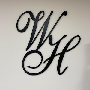 May include: Black metal wall decor featuring the letters "W" and "H" in a cursive script font.