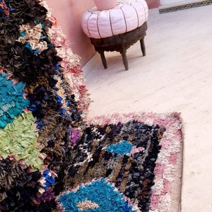 Puede incluir: Primer plano de una alfombra colorida tejida a mano con un patr&oacute;n azul, rosa y blanco. La alfombra est&aacute; hecha de materiales reciclados y tiene un aspecto texturizado &uacute;nico.
