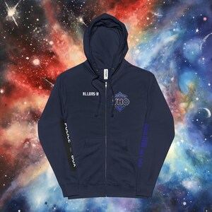 Peut inclure: Un sweat à capuche bleu marine avec fermeture éclair. Il affiche le texte "ALLONS-Y" sur la poitrine gauche et "DOCTOR WHO" avec un motif diamant sur la droite. La manche gauche porte "POLICE BOX" et la droite "BAD WOLF WILL RISE".