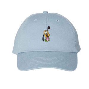 May include: A light blue baseball cap featuring an embroidered image of Pluto, a cartoon dog. The cap has a curved brim and a fabric-covered button on top. The Pluto image shows the dog's face with his tongue sticking out.
