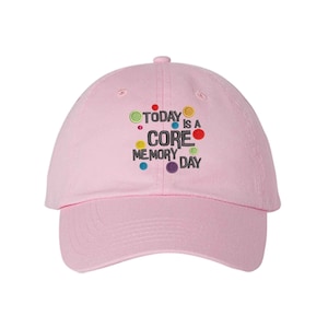 May include: Pink baseball cap with the text "TODAY IS A CORE MEMORY DAY" in black with colorful dots around the text.