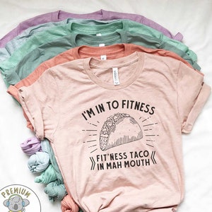 May include: A pink t-shirt with the text "I'm in to fitness fit'ness taco in mah mouth" and a black and white illustration of a taco.