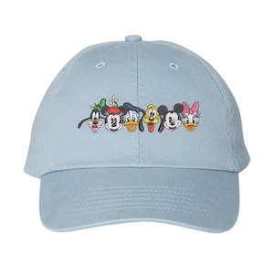 May include: A light blue baseball cap featuring embroidered cartoon character faces. The characters include Goofy, Mickey Mouse, Donald Duck, Pluto, Minnie Mouse, and Daisy Duck. The cap has a curved brim and a button on top.