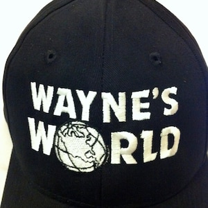 May include: A black baseball cap with a white embroidered logo that says "WAYNE'S WORLD" with a globe graphic.