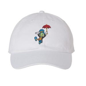May include: White baseball cap featuring an embroidered cartoon character holding a red umbrella. The character is depicted with a green face, blue hat, and a black jacket. The cap has a curved brim and a rounded crown.