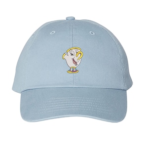 May include: Light blue baseball cap featuring an embroidered image of Chip from Beauty and the Beast. The cap has a curved brim and a six-panel design. The embroidered image is in white, yellow, and red.