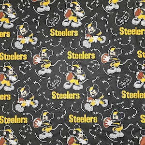 May include: Black fabric featuring a repeating pattern of a cartoon character in a football uniform holding a football. The character is wearing a black and yellow helmet and uniform. The word "Steelers" is printed in yellow.