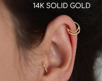 May include: A close-up of a person's ear with a gold 14k solid gold double hoop earring. The earring is made of small beads.