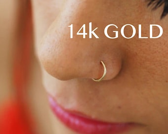 Może przedstawiać: Zbliżenie na nos osoby z małym złotym kółkiem w nosie. Tekst "14k GOLD" jest widoczny nad kółkiem.
