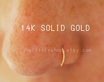 Może przedstawiać: Zbliżenie na nos osoby z małym złotym kółkiem w nosie. Tekst "14K SOLID GOLD" jest napisany nad kółkiem w nosie. Tekst "junelittleshop.etsy.com" jest napisany pod kółkiem w nosie.